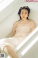 A woman sitting in a bathtub in a white dress.