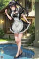 A woman in a maid outfit standing next to a pool.