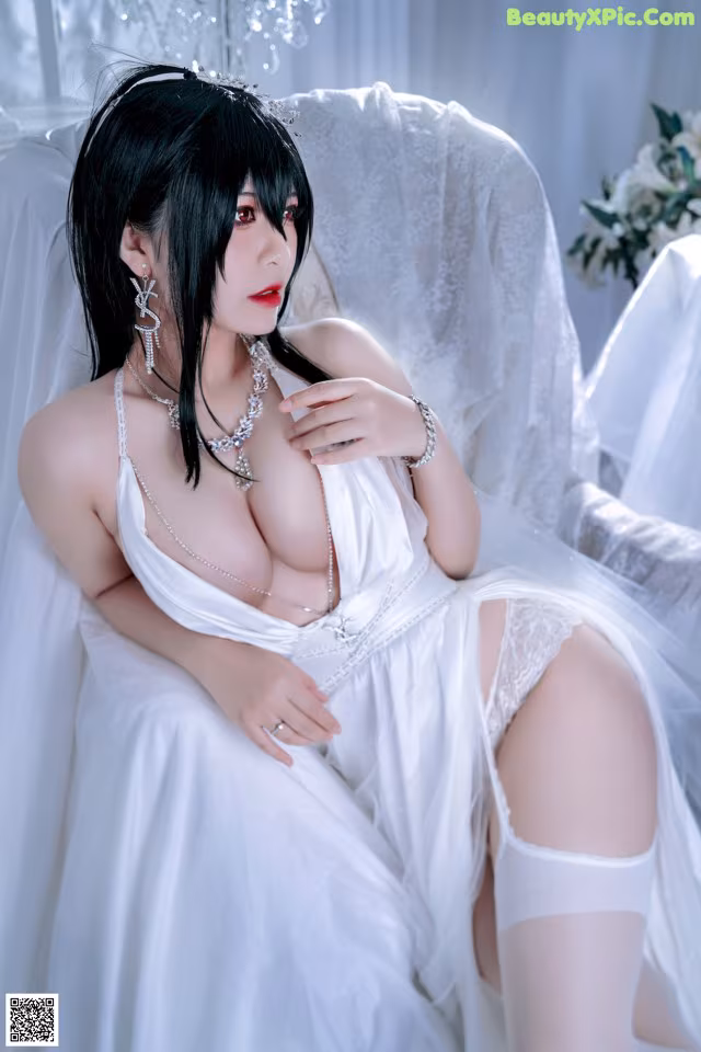 A woman in a white dress sitting on a white chair.