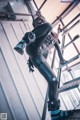 A woman in a black and blue outfit standing on a ladder.