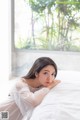 A woman laying on a bed in a white dress.