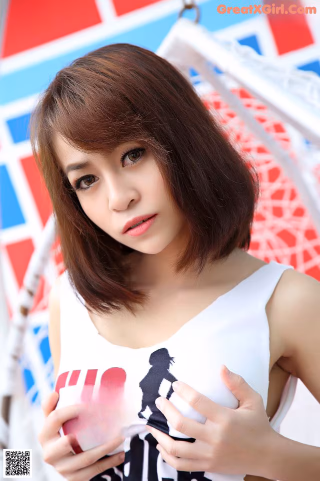 A woman in a white tank top is posing for a picture.