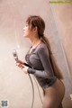 A woman standing in a shower holding a shower head.