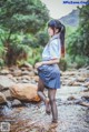 A woman in a school uniform is standing in a stream.