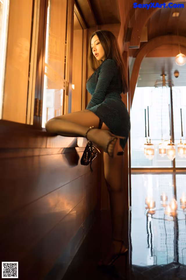 A woman in a green dress sitting on a window sill.