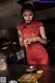 A woman in a red dress preparing food in a kitchen.