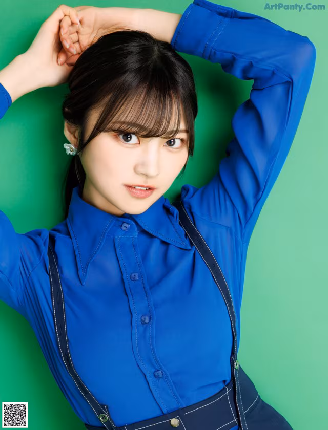 A woman in a blue shirt and suspenders posing for a picture.