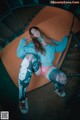 A woman in a blue sweatshirt and leggings sitting on a spiral staircase.