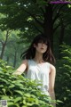 A woman in a white dress standing in the woods.