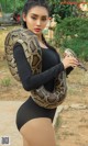 A woman holding a large snake in her hands.