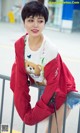 A woman in a red jacket leaning against a railing.