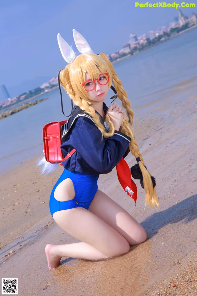 A woman in a bunny costume is sitting on the beach.