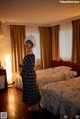 A woman standing in a hotel room next to two beds.