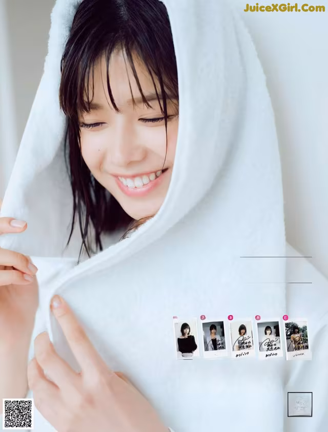 A woman wrapped in a white towel smiles at the camera.