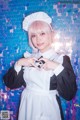 A woman in a maid outfit making a heart with her hands.