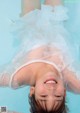 A little girl in a white dress floating in a pool.