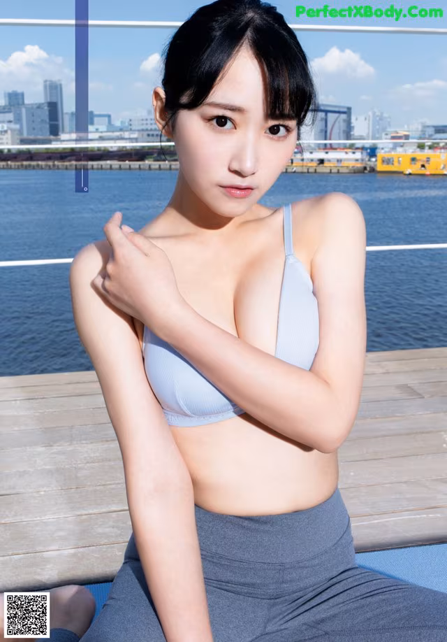 A woman in a blue bra top sitting on a dock.