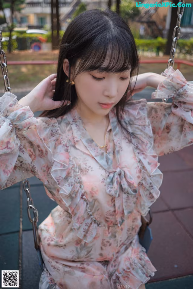 A woman sitting on a swing in a park.