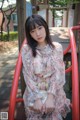 A woman sitting on a red swing in a park.