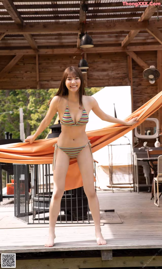 A woman in a bikini standing on a wooden deck.