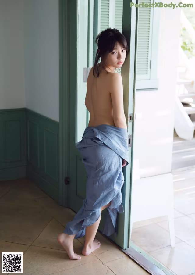A naked woman standing in front of a door.